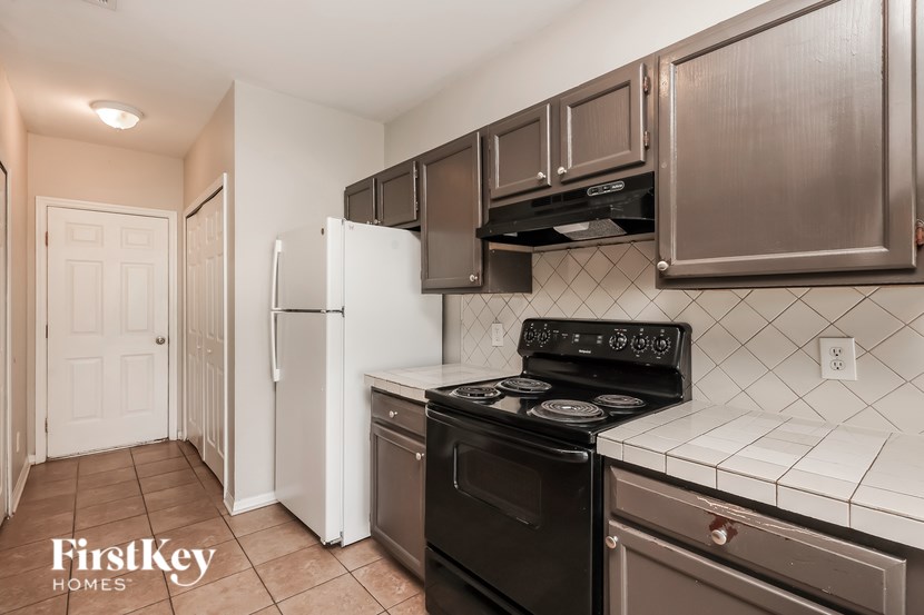 A kitchen with a stove top oven and a refrigerator.