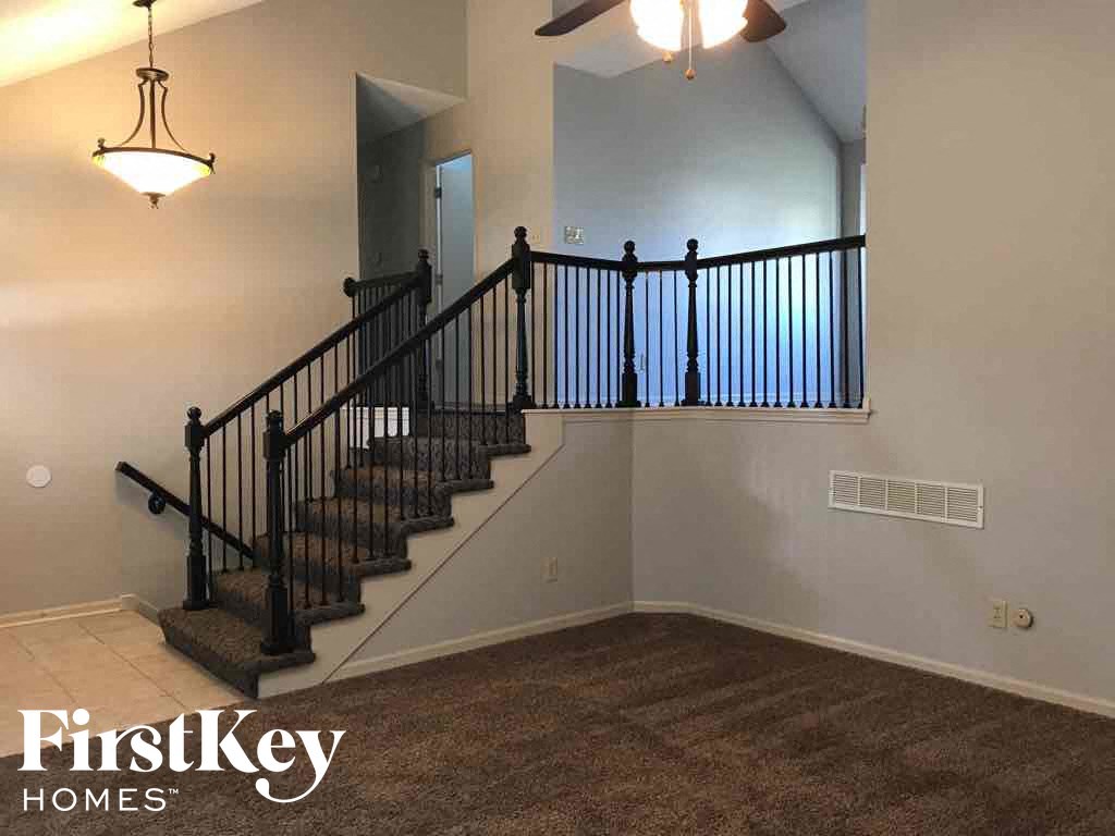 A staircase with a black railing and a light fixture above it.