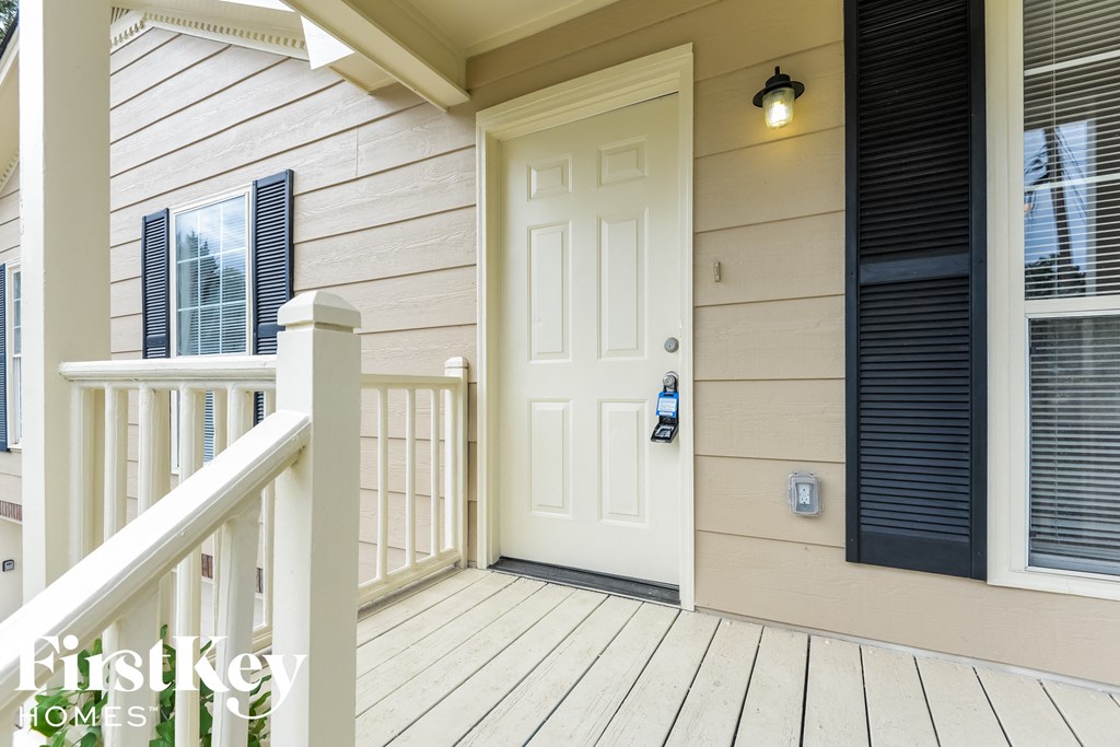 A white door with a keypad entry system is on the front porch of a house.