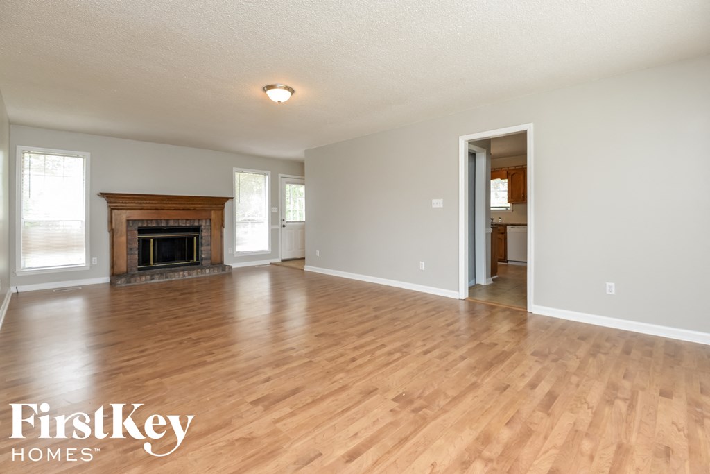 A spacious room with a fireplace and wooden floors.