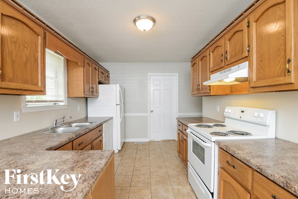A kitchen with wooden cabinets and a white stove top oven.