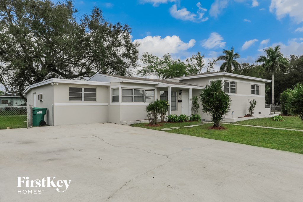 a white house with a driveway and palm trees