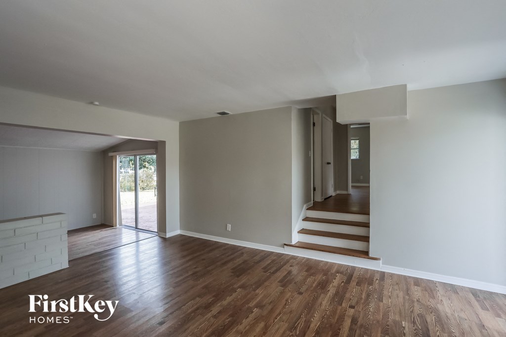 the living room and entryway of a house with wood floors and white walls