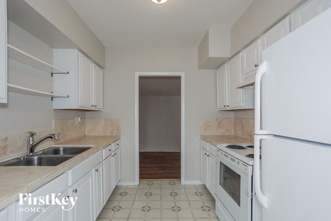 a kitchen with white cabinets and white appliances and a door to a hallway