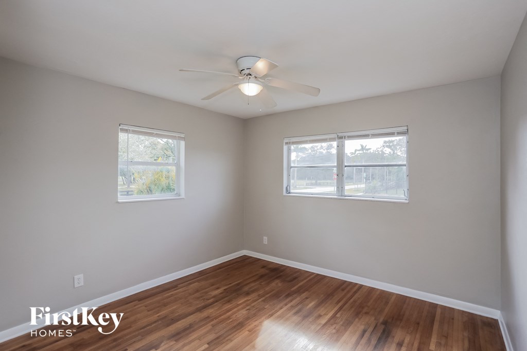 an empty room with a ceiling fan and two windows