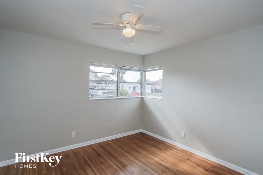 an empty room with a ceiling fan and a window
