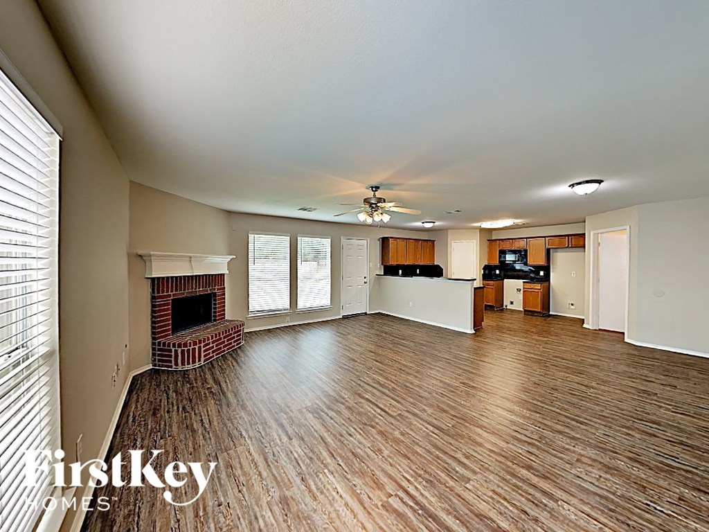 an empty living room with a fireplace and a kitchen