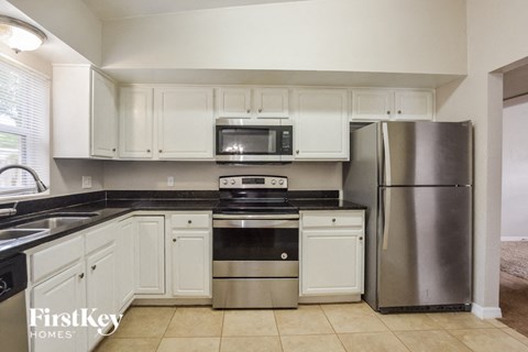 A kitchen with white cabinets and a stainless steel refrigerator.