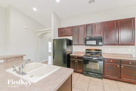 A kitchen with brown cabinets and a black refrigerator.