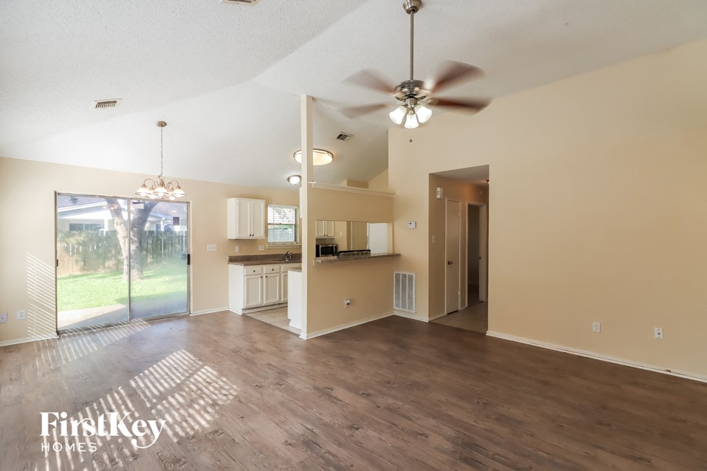 an empty living room and kitchen with a ceiling fan