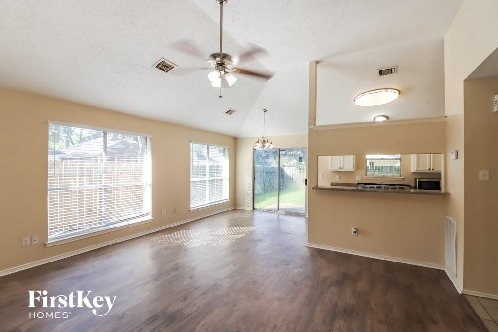 an empty living room and kitchen with a ceiling fan
