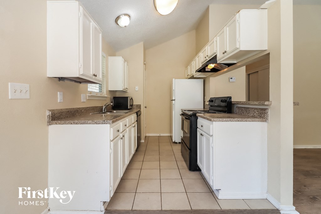 a kitchen with white cabinets and a sink and a refrigerator