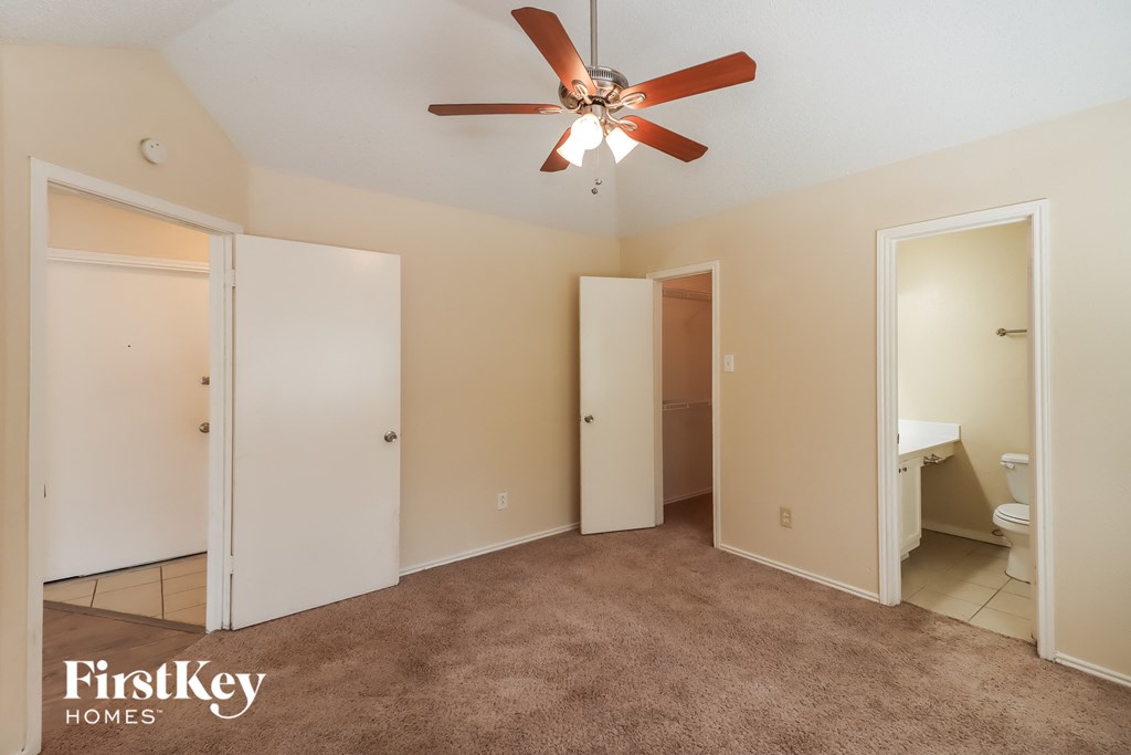a bedroom with a ceiling fan and a bathroom