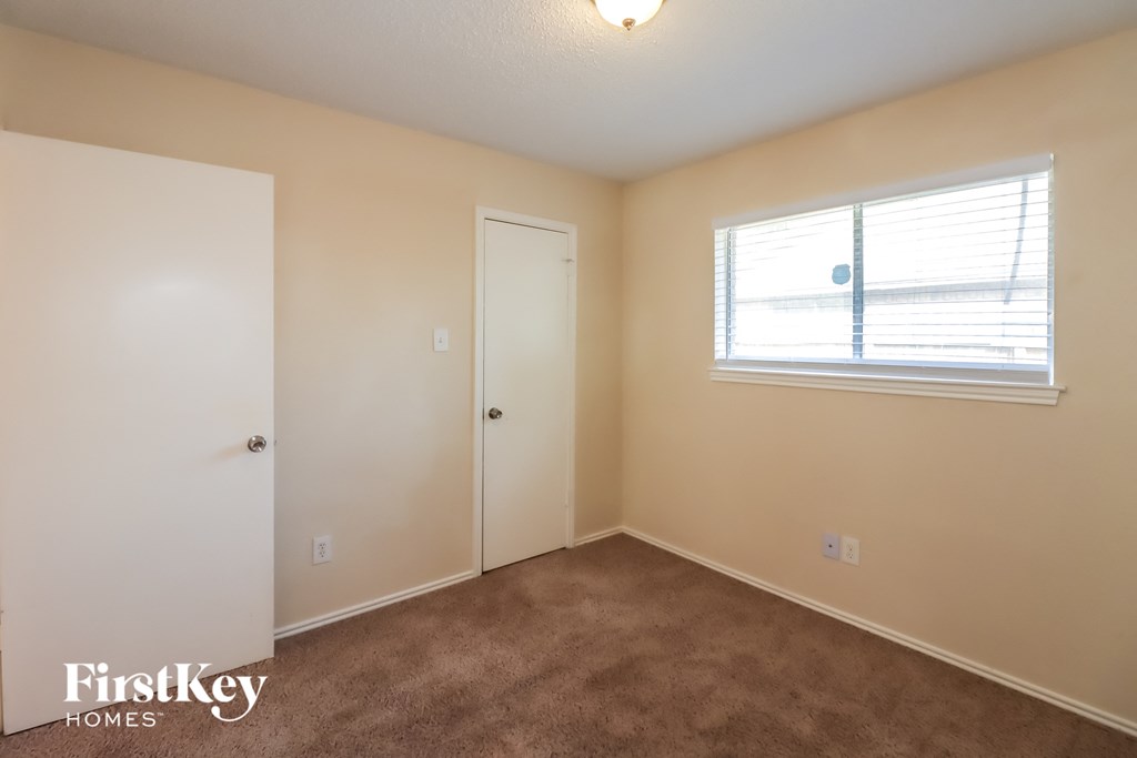 a bedroom with carpet and a window and a door