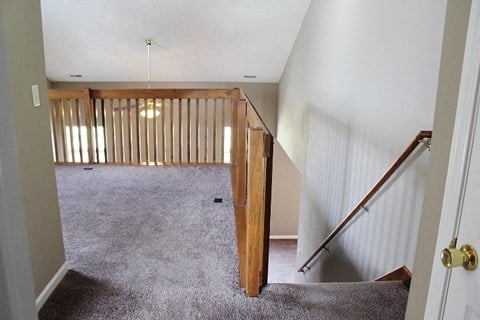 a view from the top of a staircase of a living room with carpeted stairs