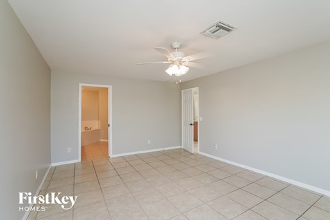 a spacious living room with tile flooring and a ceiling fan