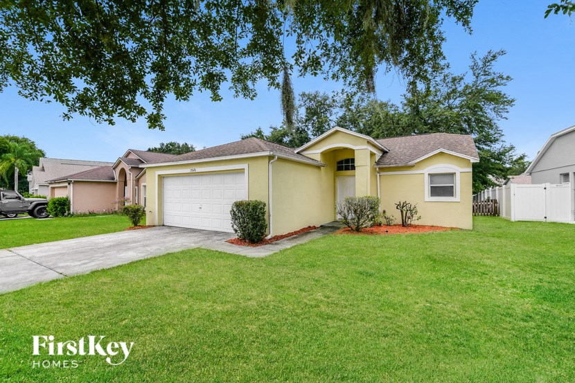a yellow house with a lawn and a driveway