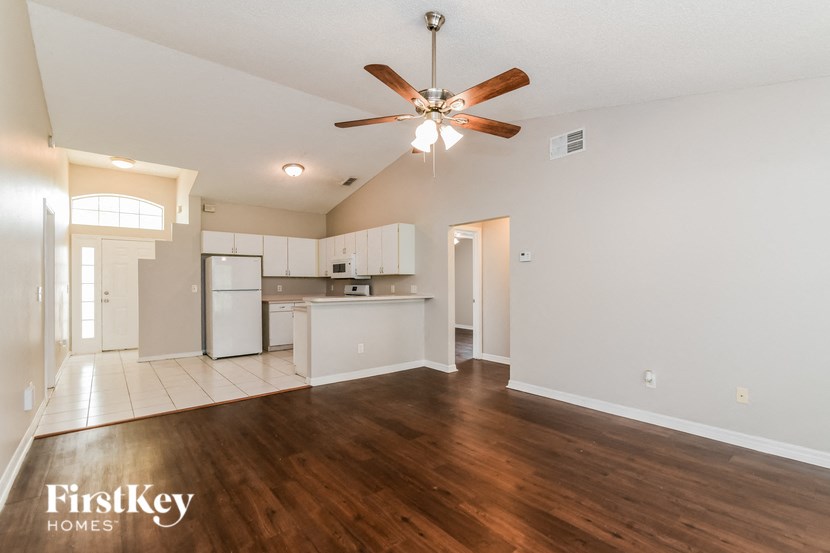 an empty living room and kitchen with a ceiling fan