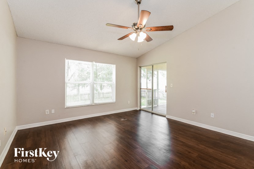 an empty living room with wood floors and a ceiling fan