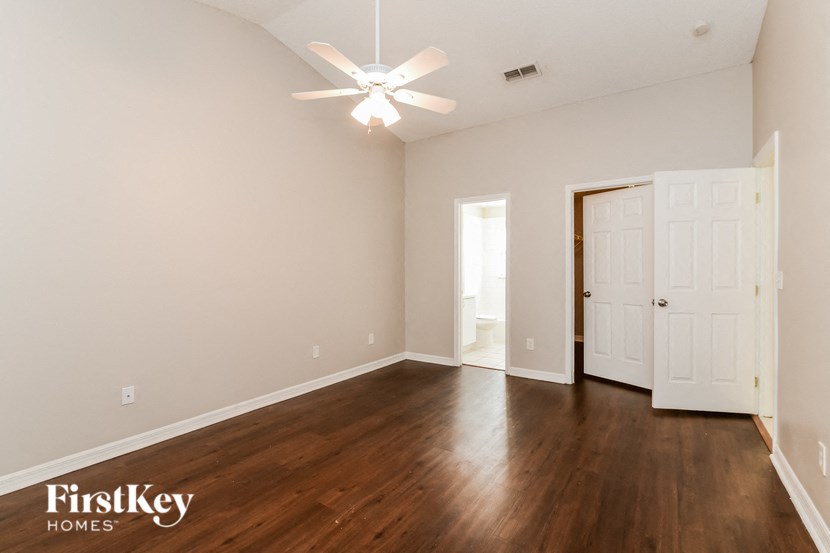 an empty living room with wood flooring and a ceiling fan