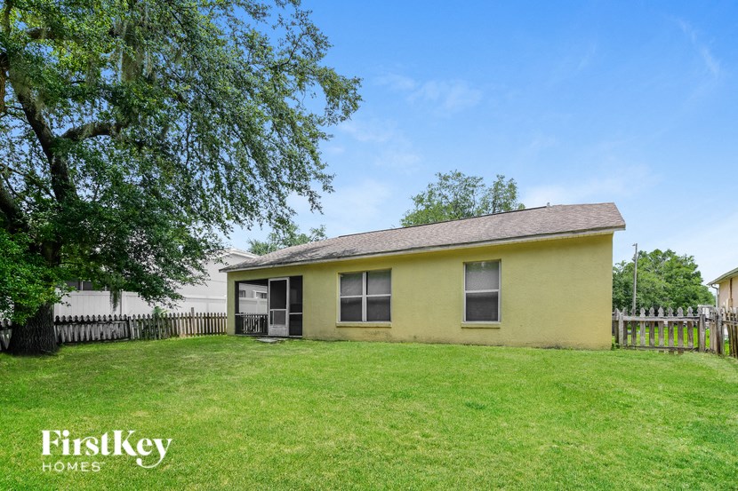 a small yellow house with a yard and a tree