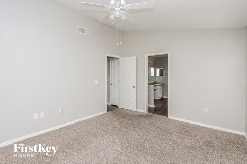 a spacious living room with carpet and a ceiling fan
