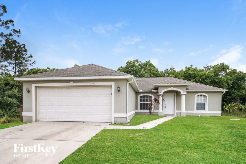 a beige house with a garage and a green lawn