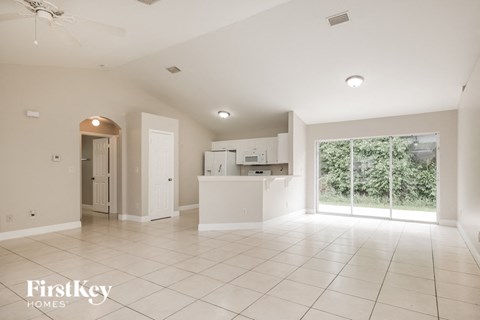 an empty living room and kitchen with a large window