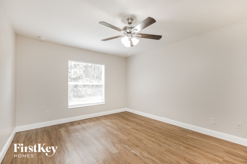 an empty bedroom with a ceiling fan and wood floors