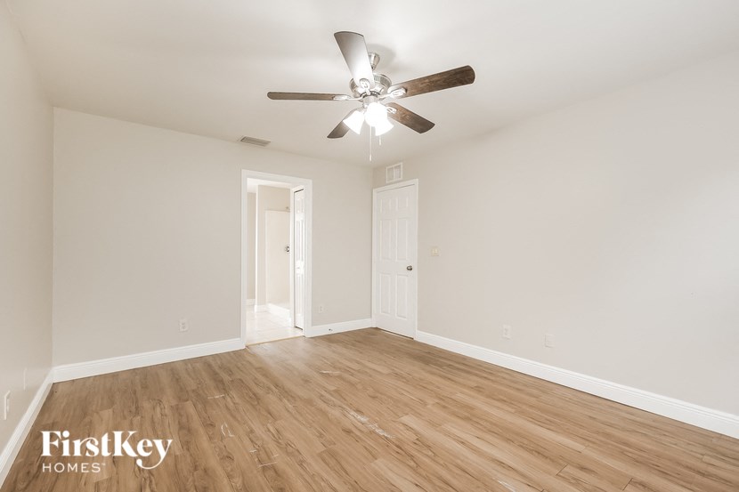 an empty living room with a ceiling fan and wood floors
