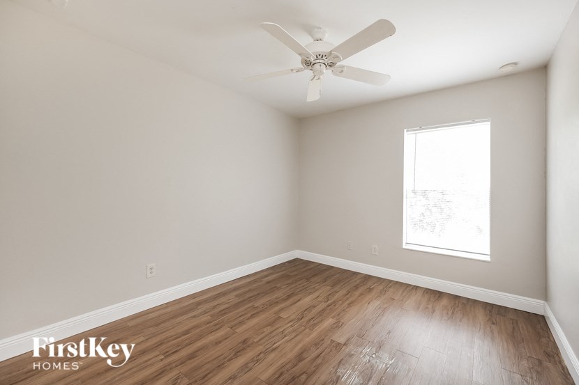 an empty room with wood flooring and a ceiling fan