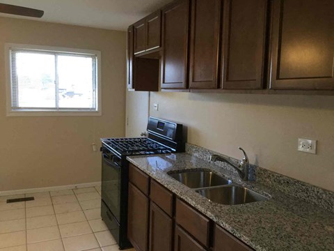 A kitchen with brown cabinets and a black stove top oven.