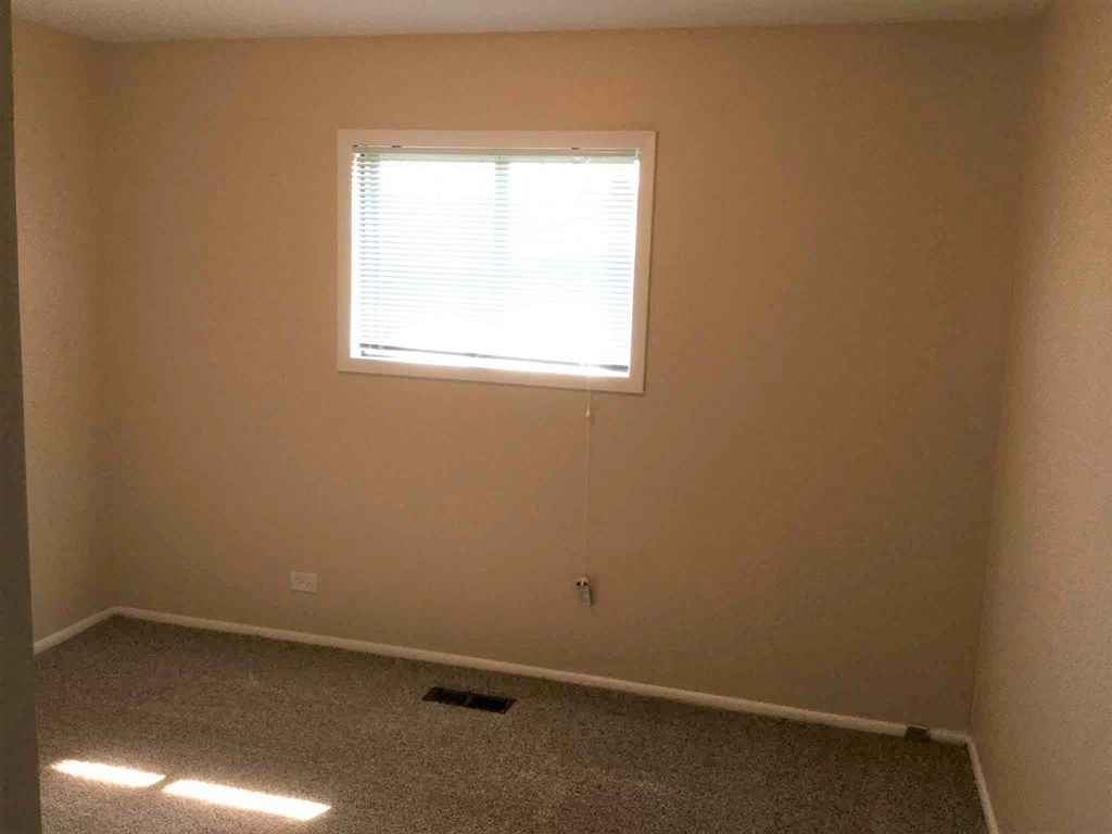 A room with a window and carpeted floor.