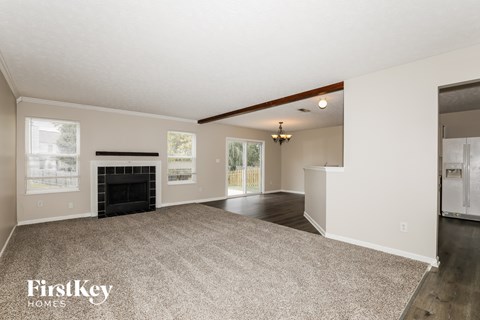 A spacious living room with a fireplace and a carpeted floor.