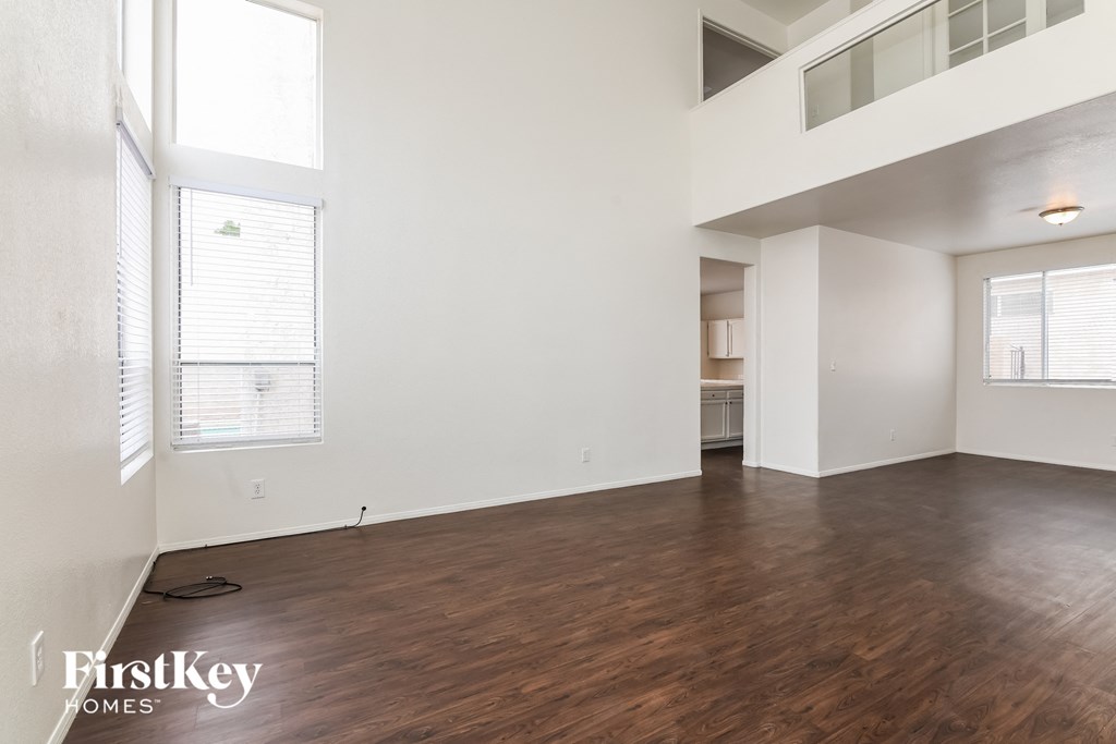 A spacious room with wooden floors and a balcony on the upper level.