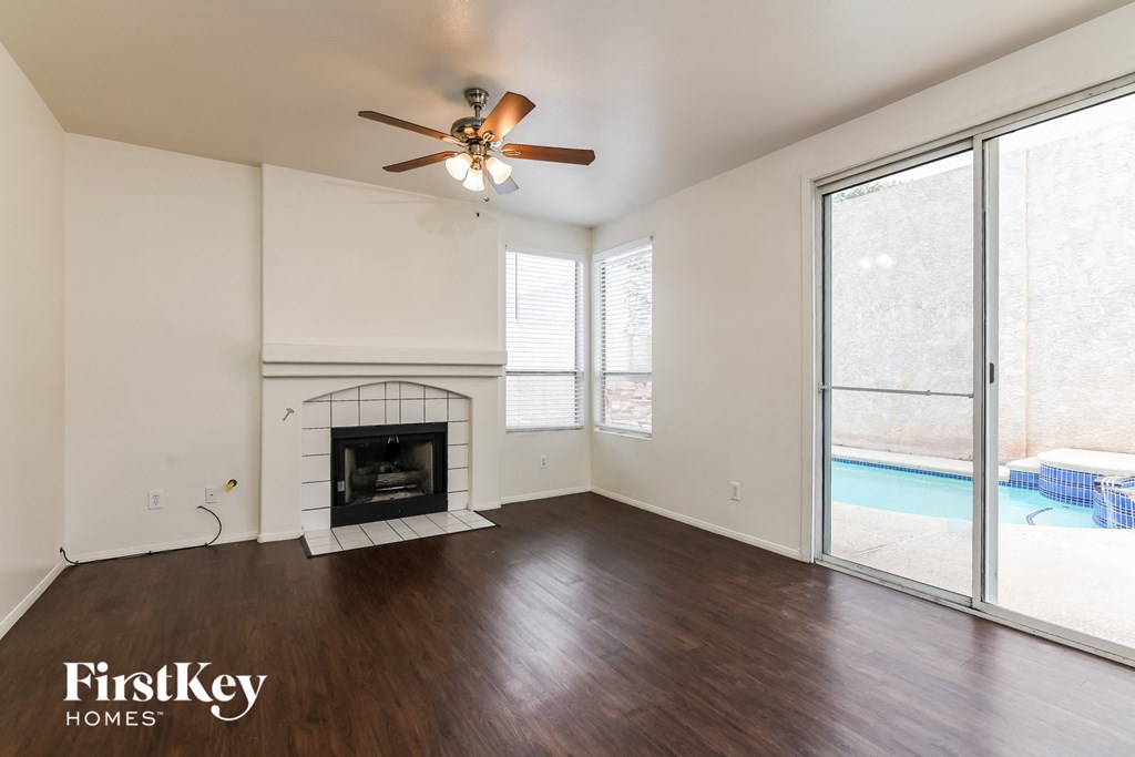 A spacious room with a fireplace and sliding glass doors leading to a pool.