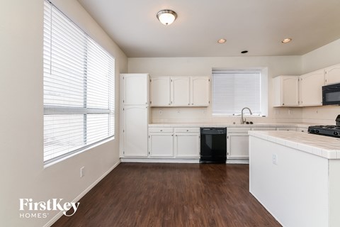 A kitchen with white cabinets and a black dishwasher.