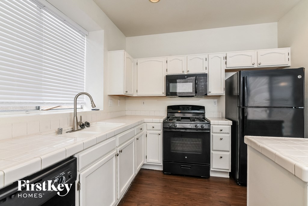 A kitchen with white cabinets and black appliances.