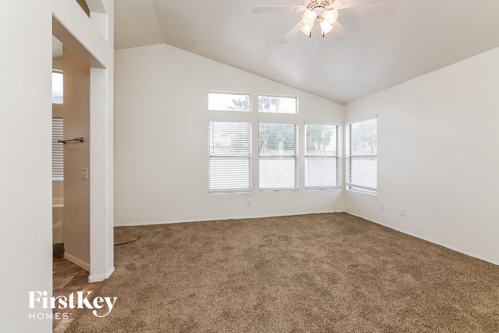 A room with a carpeted floor and a ceiling fan.
