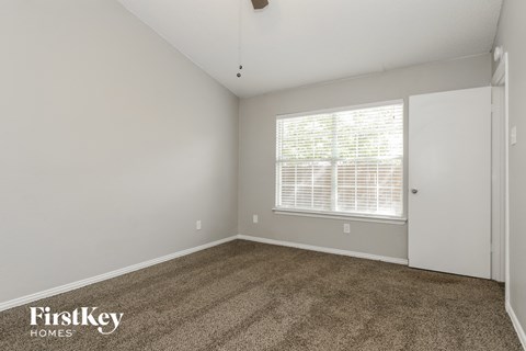 the living room of an apartment with carpet and a large window