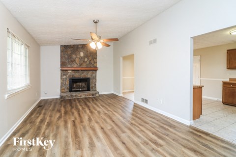A spacious room with a fireplace and wood flooring.