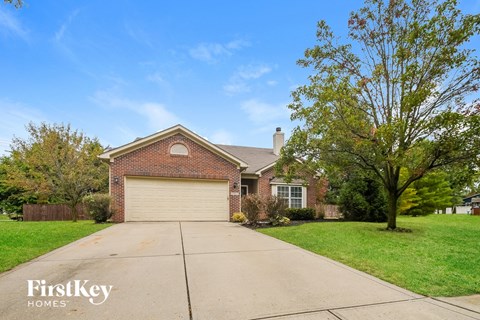 A house with a garage and a tree in front.