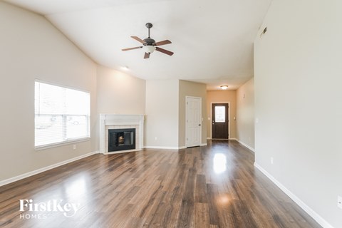 A spacious room with a fireplace and a ceiling fan.