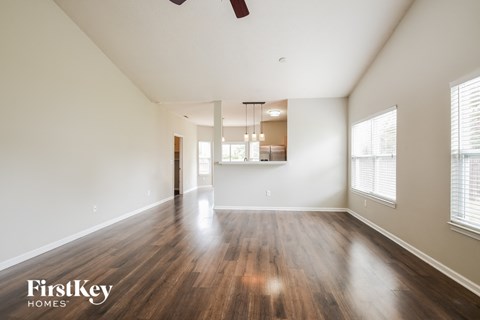 A spacious room with wooden floors and a ceiling fan.