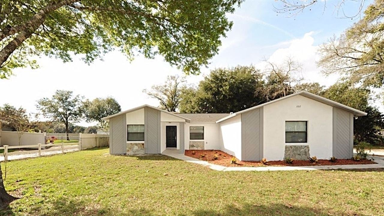 a small white house with a yard and a tree