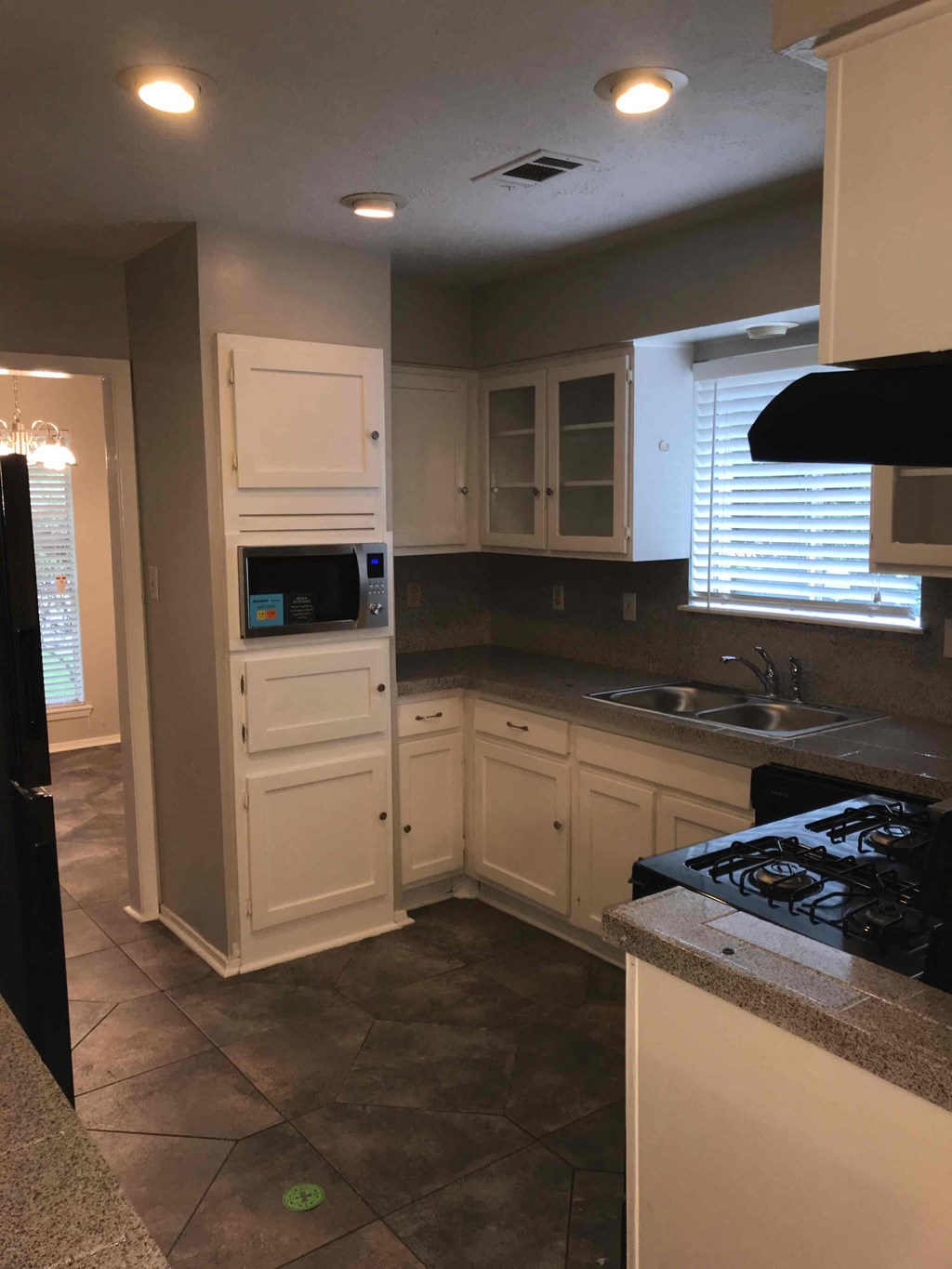 A kitchen with a stove, sink, and cabinets.
