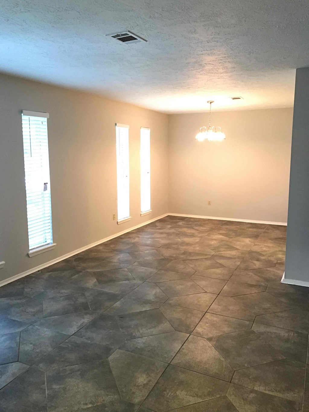 A room with a stone floor and a chandelier.