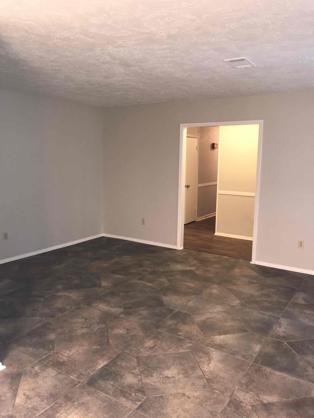 A room with a stone floor and a doorway leading to another room.