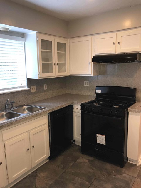 A black oven is in a kitchen with white cabinets.
