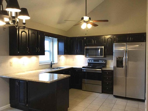 A kitchen with black cabinets and stainless steel appliances.